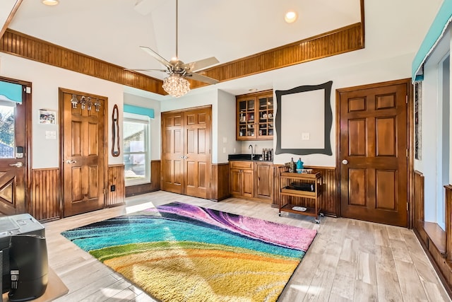 interior space featuring multiple windows, ceiling fan, wooden walls, and light hardwood / wood-style floors