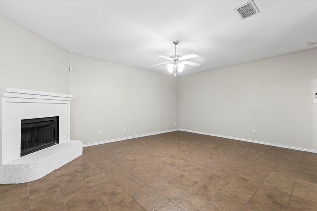 unfurnished living room with tile patterned flooring, ceiling fan, and a brick fireplace