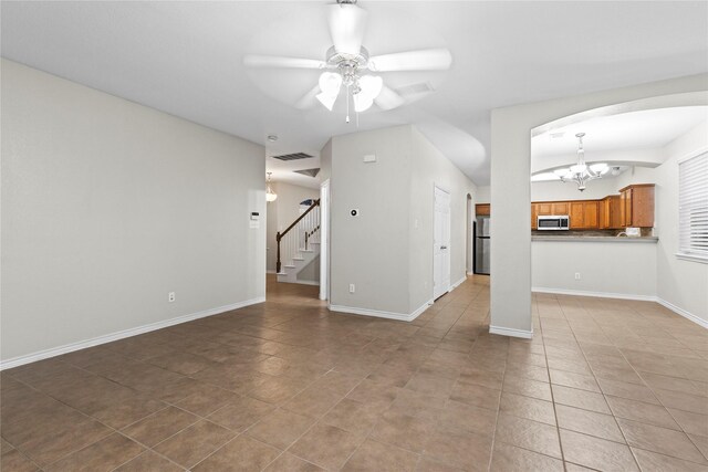 unfurnished living room featuring light tile patterned flooring and ceiling fan with notable chandelier