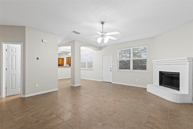 unfurnished living room with ceiling fan, a fireplace, and light tile patterned floors