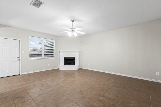 unfurnished living room with ceiling fan and a fireplace