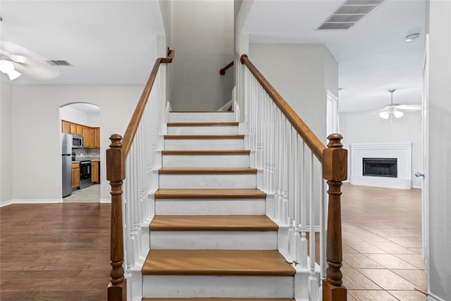 stairway with ceiling fan and wood-type flooring