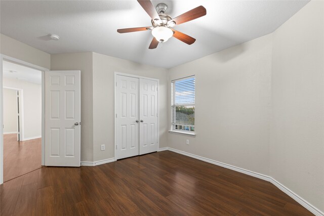 unfurnished bedroom with dark hardwood / wood-style flooring, a closet, and ceiling fan