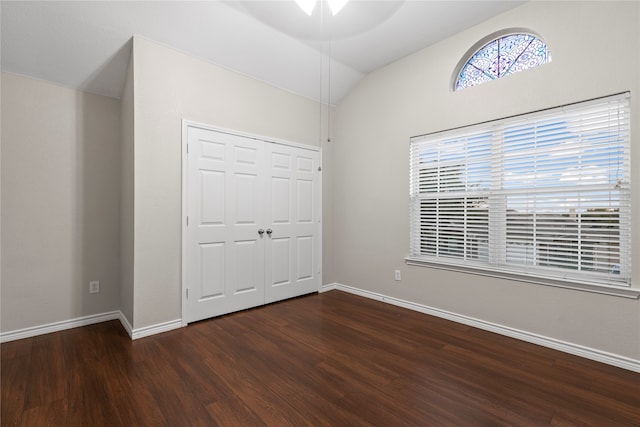 unfurnished bedroom with dark hardwood / wood-style flooring, vaulted ceiling, a closet, and ceiling fan