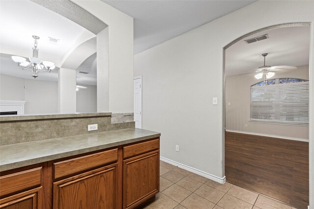 kitchen featuring light hardwood / wood-style flooring, pendant lighting, and ceiling fan with notable chandelier