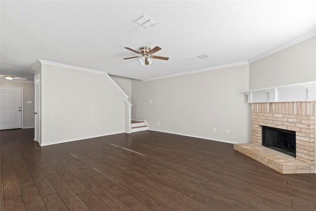 unfurnished living room with crown molding, dark hardwood / wood-style flooring, a textured ceiling, and a brick fireplace