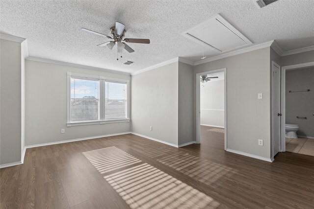 empty room with a textured ceiling, crown molding, and dark wood-type flooring