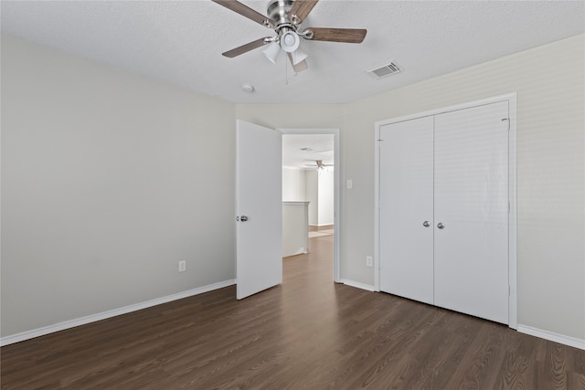 unfurnished bedroom featuring ceiling fan, dark hardwood / wood-style floors, a textured ceiling, and a closet