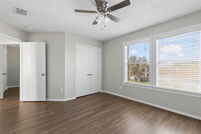 unfurnished bedroom featuring a textured ceiling, ceiling fan, dark wood-type flooring, and a closet