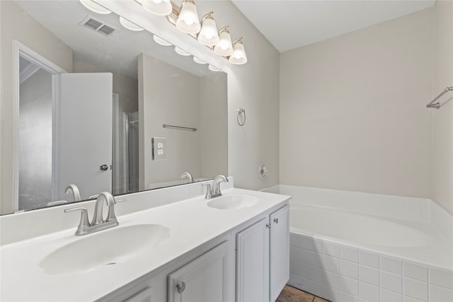 bathroom featuring vanity, tile patterned floors, and tiled tub