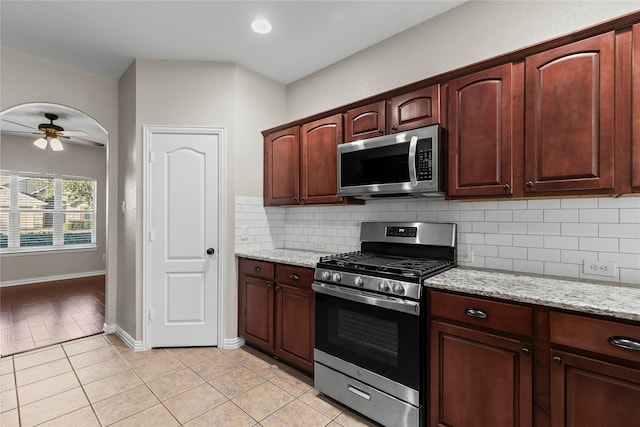 kitchen with light stone countertops, tasteful backsplash, stainless steel appliances, ceiling fan, and light tile patterned floors