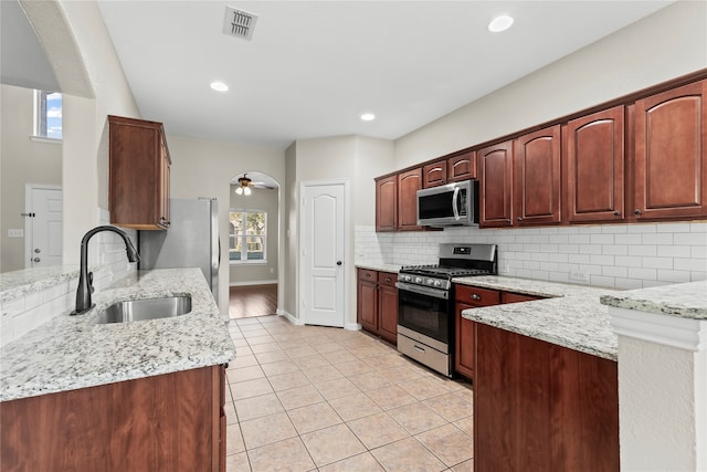 kitchen featuring sink, light stone counters, stainless steel appliances, and a wealth of natural light