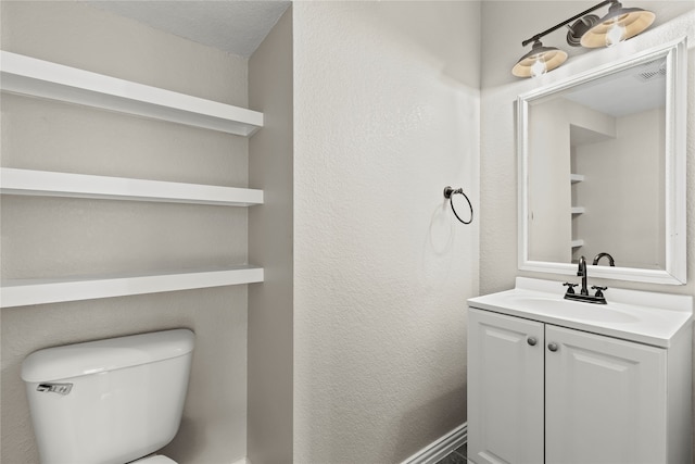 bathroom featuring a textured ceiling, vanity, and toilet