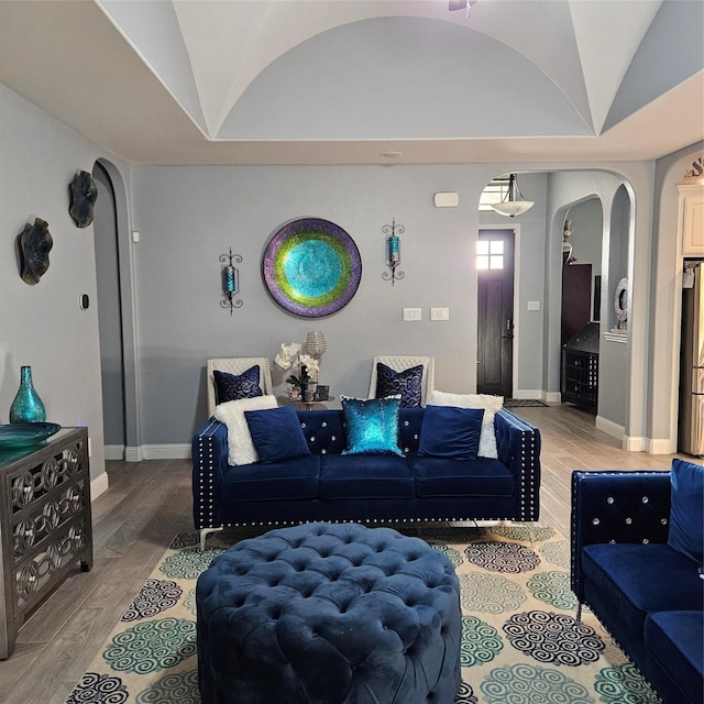 living room featuring lofted ceiling and light hardwood / wood-style floors