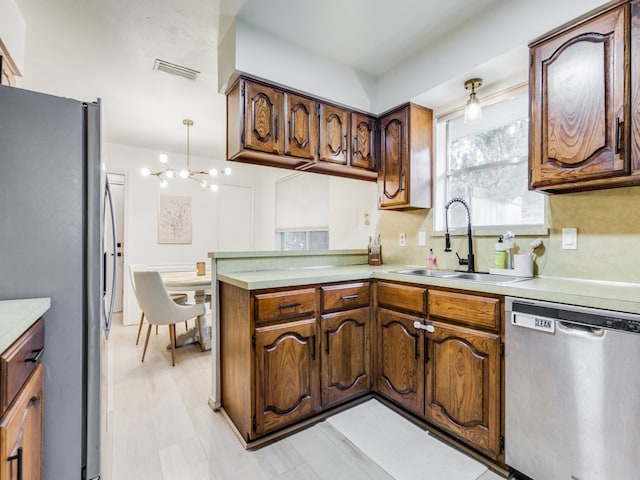 kitchen featuring an inviting chandelier, sink, hanging light fixtures, kitchen peninsula, and stainless steel appliances