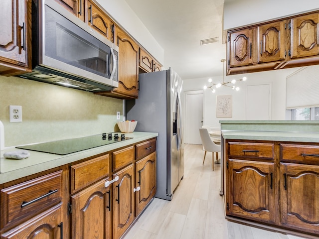 kitchen with light hardwood / wood-style flooring, a chandelier, and appliances with stainless steel finishes