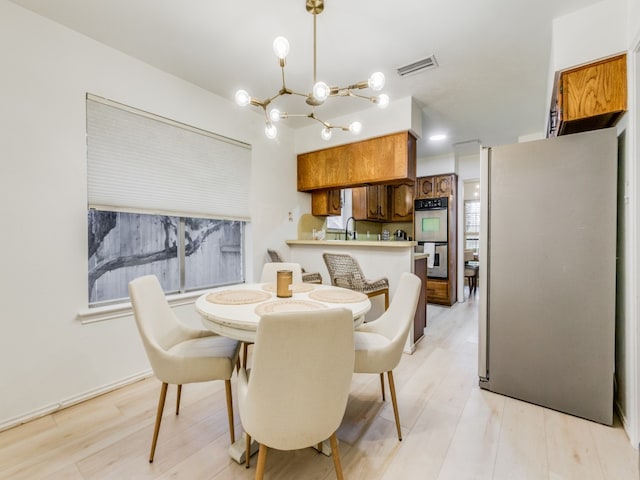 dining room with sink, a chandelier, and light wood-type flooring