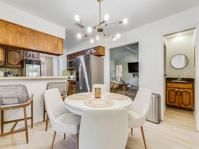 dining room with light hardwood / wood-style floors, lofted ceiling, sink, and an inviting chandelier