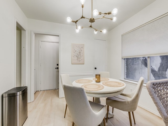 dining area with light hardwood / wood-style floors and a notable chandelier