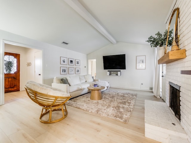 living room featuring light hardwood / wood-style flooring, lofted ceiling with beams, and a brick fireplace