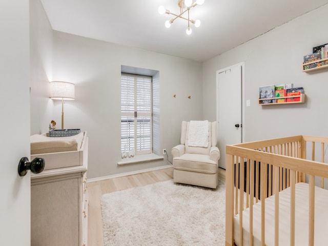 bedroom with a chandelier, hardwood / wood-style flooring, and a nursery area