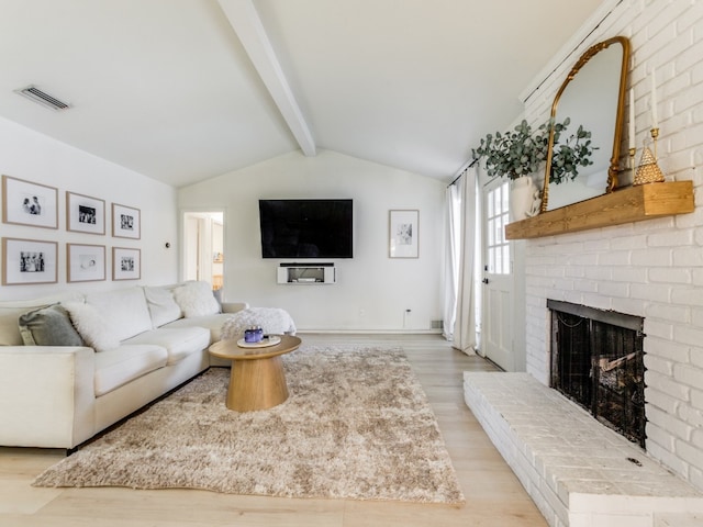 living room with vaulted ceiling with beams, a fireplace, and light hardwood / wood-style floors