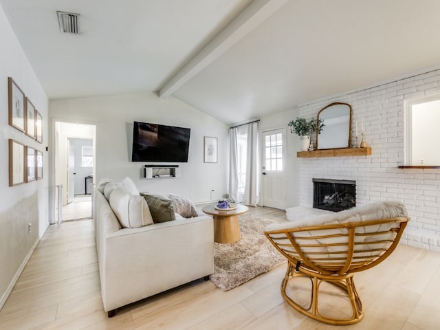 living room with a brick fireplace, vaulted ceiling with beams, and light hardwood / wood-style flooring