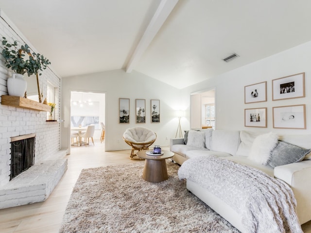 living room featuring a fireplace, lofted ceiling with beams, and light hardwood / wood-style flooring