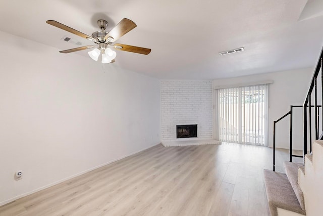 unfurnished living room with ceiling fan, a fireplace, and light hardwood / wood-style flooring