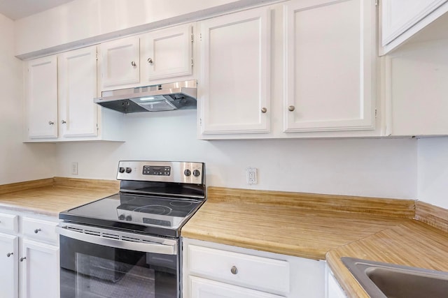 kitchen with stainless steel electric range and white cabinetry