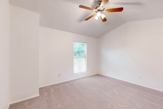 carpeted spare room with ceiling fan and vaulted ceiling