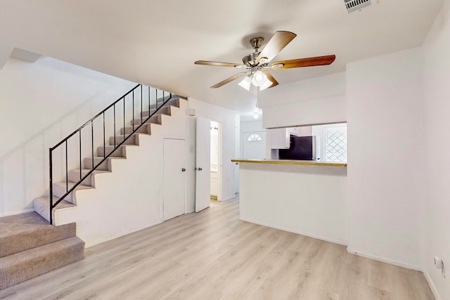 unfurnished living room featuring ceiling fan and light wood-type flooring