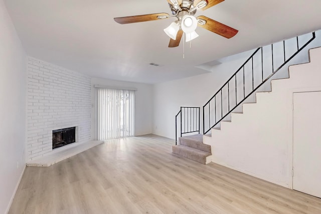 unfurnished living room with ceiling fan, light hardwood / wood-style floors, and a brick fireplace