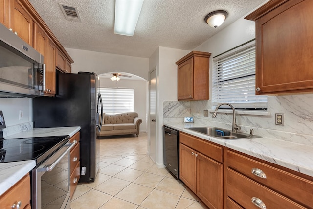 kitchen featuring appliances with stainless steel finishes, tasteful backsplash, ceiling fan, sink, and light tile patterned floors