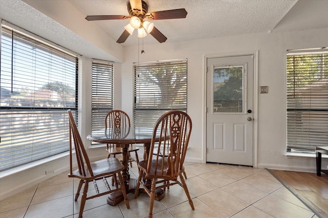 tiled dining room with ceiling fan and a textured ceiling