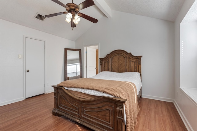 bedroom featuring ceiling fan, light hardwood / wood-style flooring, lofted ceiling with beams, and a textured ceiling