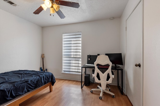 bedroom featuring ceiling fan, a textured ceiling, and light wood-type flooring