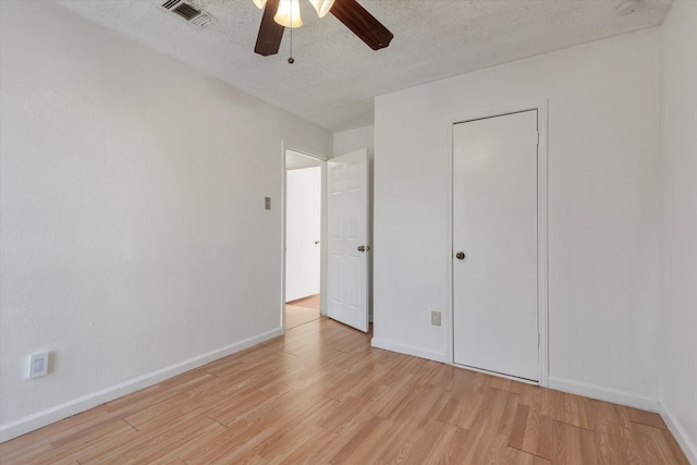 unfurnished bedroom featuring a closet, a textured ceiling, light hardwood / wood-style floors, and ceiling fan