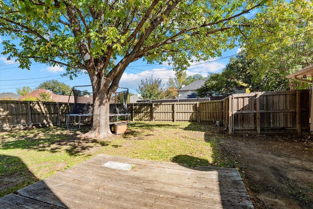 view of yard featuring a wooden deck and a trampoline