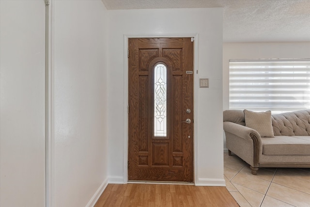 foyer entrance with a textured ceiling and light hardwood / wood-style flooring