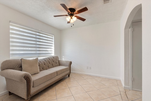 tiled living room with ceiling fan and a textured ceiling