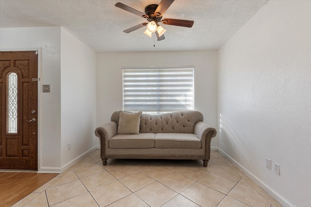 living area with ceiling fan, a textured ceiling, and light wood-type flooring