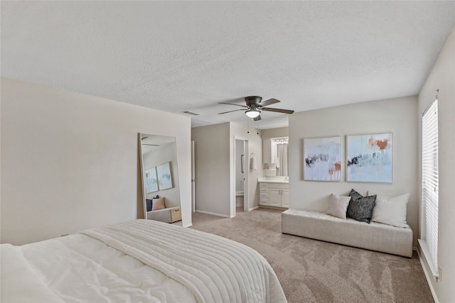 bedroom featuring ensuite bath, ceiling fan, light carpet, and a textured ceiling