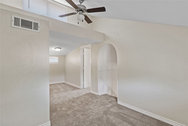 carpeted spare room with ceiling fan and vaulted ceiling