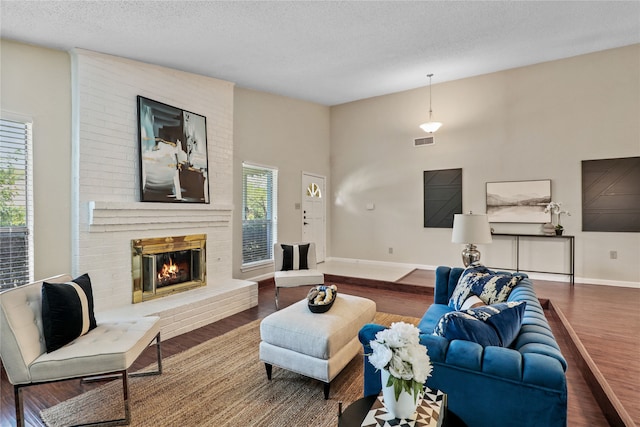 living room featuring plenty of natural light, a fireplace, wood-type flooring, and a textured ceiling