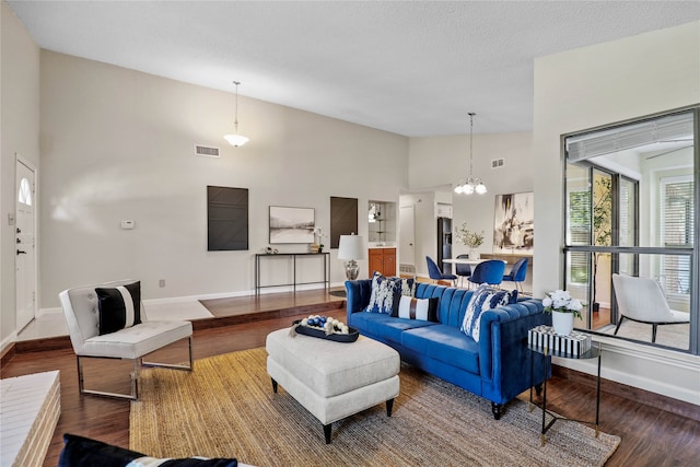 living room with hardwood / wood-style floors, a textured ceiling, high vaulted ceiling, and an inviting chandelier