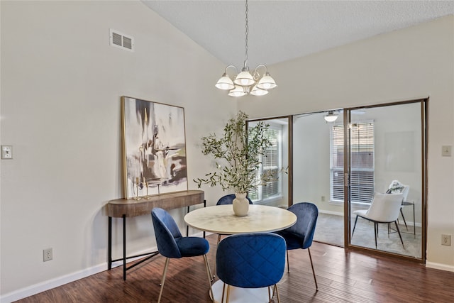 dining area featuring a textured ceiling, a notable chandelier, lofted ceiling, and dark wood-type flooring