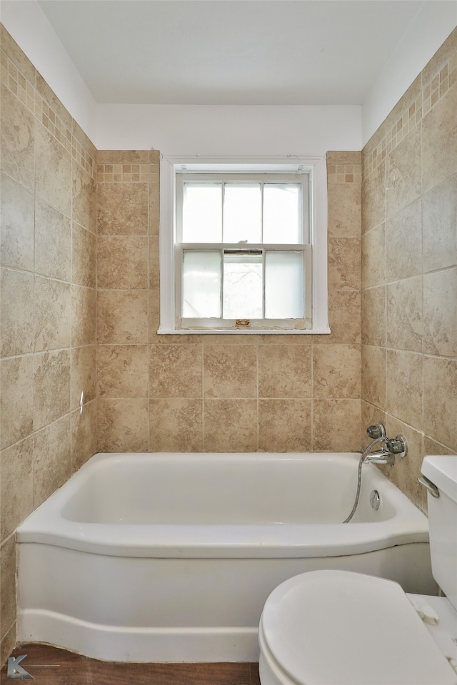 bathroom featuring a tub to relax in, toilet, tile walls, and hardwood / wood-style flooring