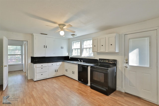 kitchen with a wealth of natural light, light hardwood / wood-style flooring, white cabinets, and black appliances