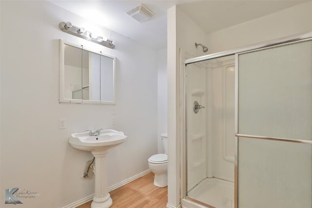 bathroom featuring hardwood / wood-style floors, toilet, and a shower with shower door